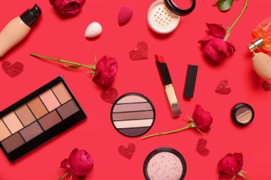 Kırmızı arka planda gülleri ve kalpleri olan kozmetik ürünleri. Sevgililer Günü kutlaması