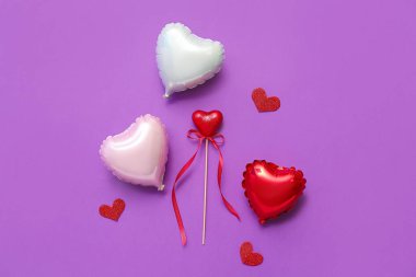 Kalp şeklinde hava balonları ve mor arka planda dekorasyonlar. Sevgililer Günü kutlaması