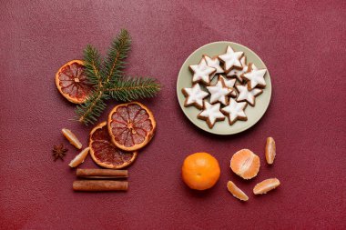 Lezzetli yıldızlı tabak. Noel kurabiyeleri şekillendirilmiş. Kurumuş portakal parçaları ve kahverengi arka planda mandalina.
