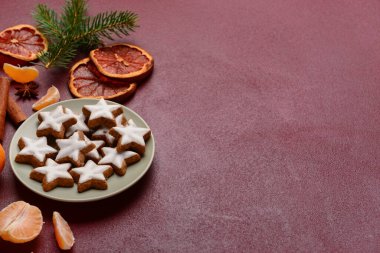 Lezzetli yıldızlı tabak. Noel kurabiyeleri şekillendirilmiş. Kurumuş portakal parçaları ve kahverengi arka planda mandalina.