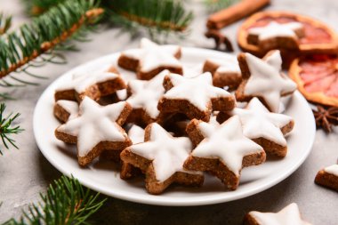 Gri arkaplanda lezzetli yıldızlı tabak şekilli Noel kurabiyeleri.