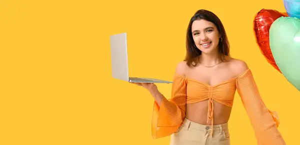 Dizüstü Bilgisayarı Sarı Arka Planda Balonları Olan Genç Bir Kadın — Stok fotoğraf