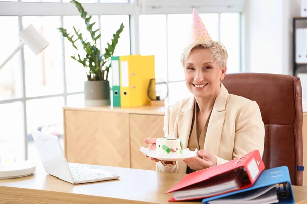 Mature woman with birthday cake in office