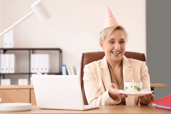 Mature woman with birthday cake in office