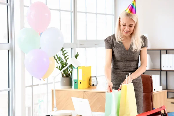 Mature woman with bags of gifts in office