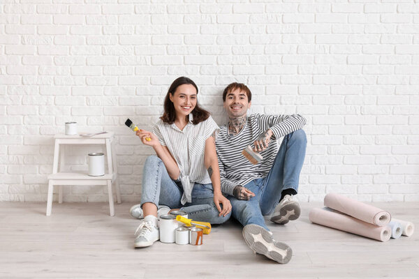Молодая пара с кисточками во время ремонта в своем новом доме