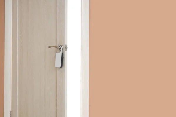 Open wooden door with hanger in hotel room, closeup