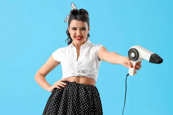 Attractive pin-up woman with hair dryer on blue background