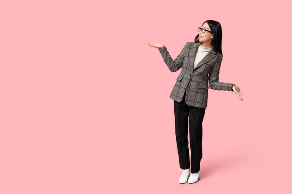 Portrait of confused Asian businesswoman on pink background