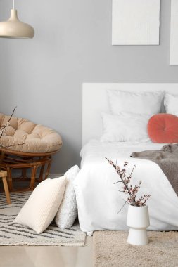 Şık yatak odasının içi vazolarda çiçek açan ağaç dallarıyla süslenmiş.