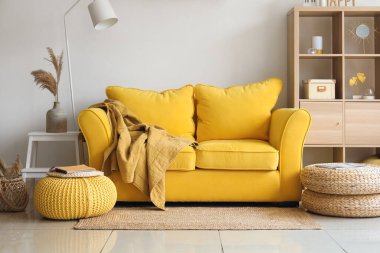 Işıl ışıl oturma odasının içinde şık sarı koltuklar ve yumuşak puflar.