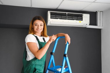 Klimalı kadın teknisyen odada baş parmak gösteriyor.