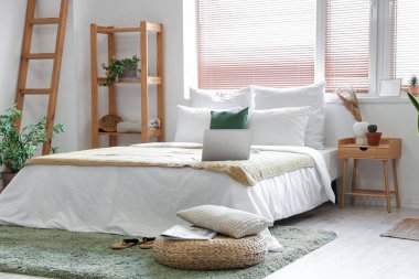 Şık yatak odasının içinde rattan puf var.