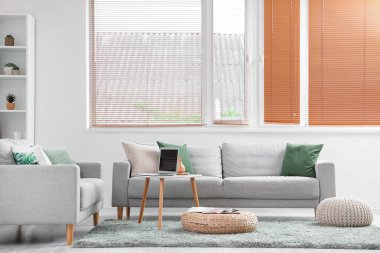 Oturma odasının içinde kanepeler, masa ve rattan pouf