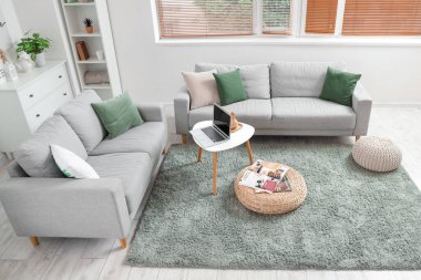 Oturma odasının içinde kanepeler, masa ve rattan pouf