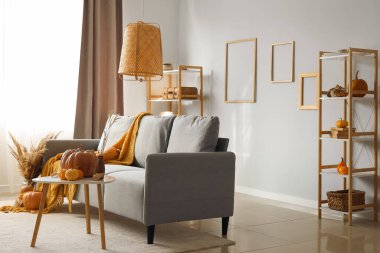 Gri koltuklu, kahve masalı ve balkabaklı bir sonbahar salonu.