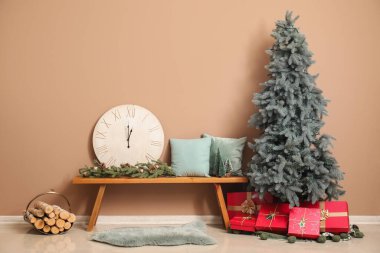 Güzel dekore edilmiş Noel ağacı Bej duvarın yanındaki bankta büyük bir saat