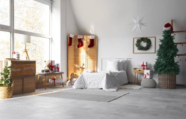 Rahat yatağı ve Noel süslemeleri olan neşeli çocukların yatak odasının içi.