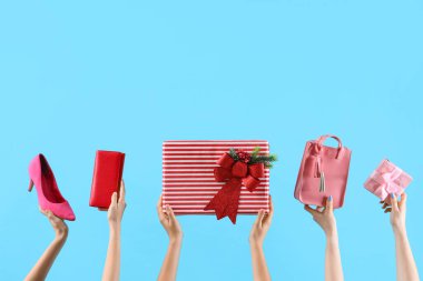 Mavi arka planda Noel hediyesi kutuları, çantaları ve ayakkabıları olan bir sürü el.