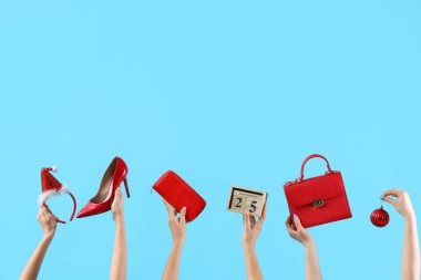 Mavi arka planda Noel süslemeleri, ayakkabıları ve çantası olan birçok el.