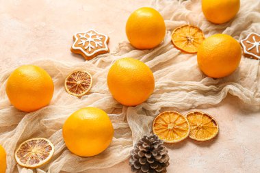 Tatlı Noel kurabiyeleri ve bej arka planda çam kozalağı olan lezzetli portakallar.