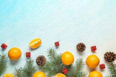 Köknar dallı lezzetli portakallar, çam kozalakları ve açık mavi arka planda hediye kutuları.