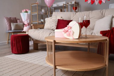 Kalp şeklinde hediye kutuları. Oturma odasındaki masada bardaklar dolusu şarap. Sevgililer Günü için dekore edilmiş.