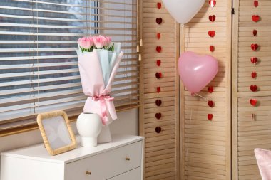 Sevgililer Günü için dekore edilmiş odalardaki çekmecelerin üzerinde güller ve boş çerçeveli vazolar.