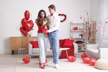 Sevgililer Günü 'nü evde gül taşıyan genç bir çift.