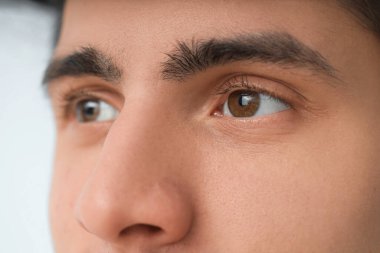Açık arka planda kahverengi gözlü genç adam, yakın plan. Glaucoma farkındalık ayı