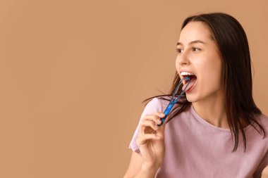 Kahverengi arka planda dil kazıyıcısı olan güzel genç bir kadın.