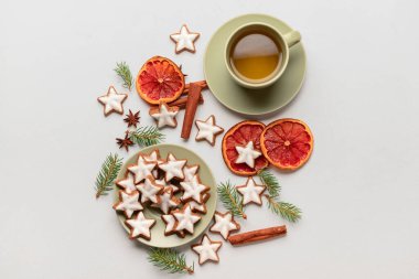 Lezzetli yıldızlı kompozisyon Noel kurabiyeleri, bir fincan çay, baharatlar ve arka planda köknar ağacı dalları