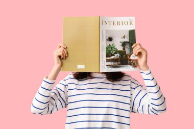 Pembe arka planda dergi okuyan genç bir kadın.