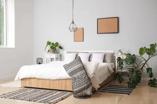 Interior of modern bedroom with comfortable double bed, white pillows and houseplants