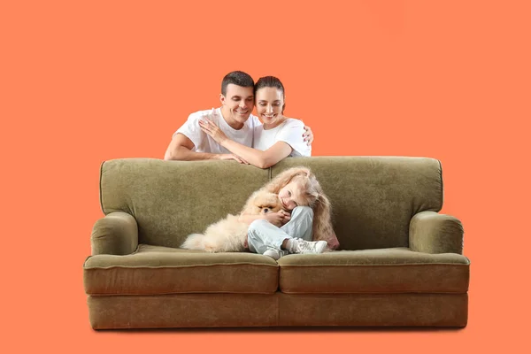 Happy family with dog and sofa on orange background