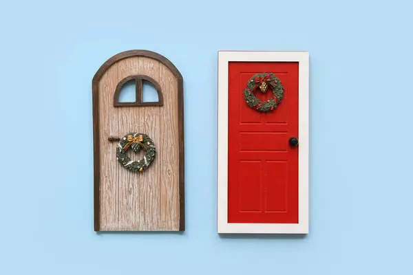 Beautiful composition with two doors and Christmas wreath on blue background