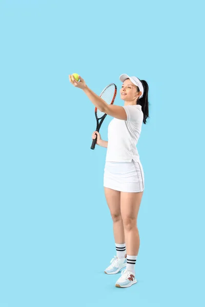 Female tennis player with racket and ball on blue background
