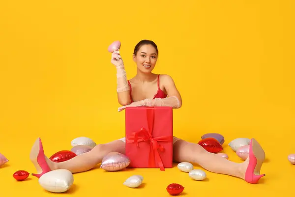 美丽而性感的亚洲女人 带着礼品盒和心形气球坐在黄色的背景上 情人节庆祝活动 — 图库照片