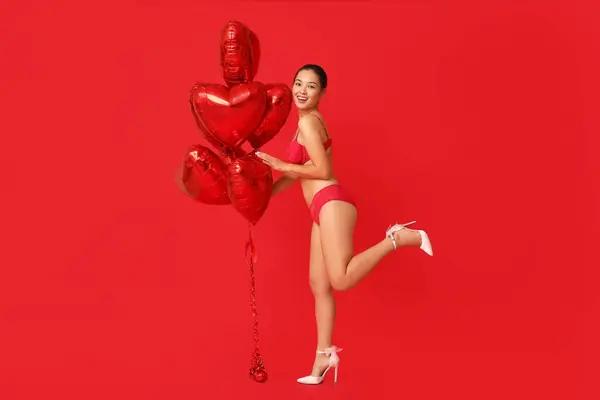 漂亮的年轻快乐的亚洲女人 穿着性感内裤 红底上有心形气球 情人节庆祝活动 — 图库照片