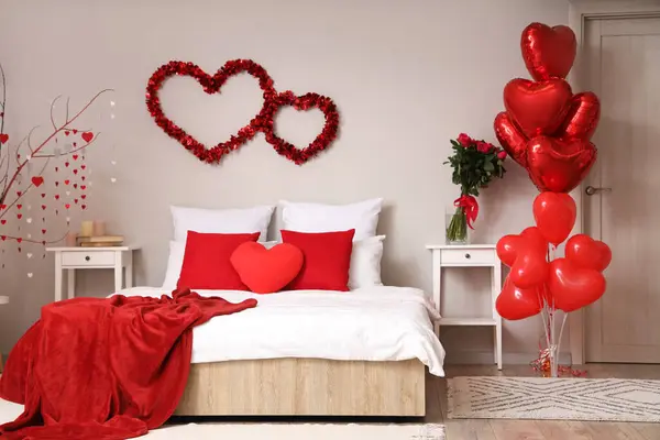 Interior of light bedroom decorated for Valentine\'s Day with hearts, balloons and roses