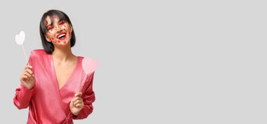 Sevgililer Günü için yaratıcı makyajı olan şık genç bir kadın ve gri arkaplanda yazı için yeri olan kağıt kalpler.