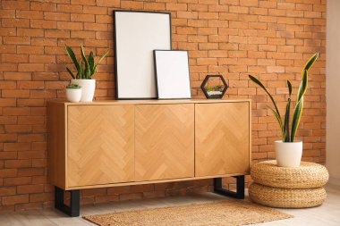 Boş çerçeveli ahşap dolap ve kahverengi tuğla duvarın yanında bitkiler.