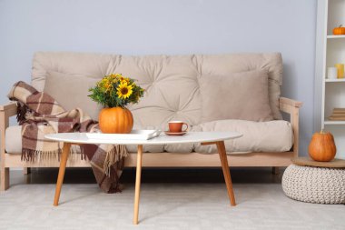 Sonbahar çiçekli balkabağı ve oturma odasındaki masada bir fincan kahve.