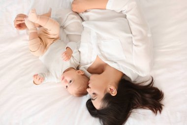 Mutlu bir anne, küçük bebeği yatakta uzanmış, manzarası güzel.