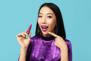 Mavi arka planda ruj izi olan güzel bir Asyalı kadın.
