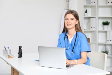 Ofiste dizüstü bilgisayarla çalışan kadın doktor.