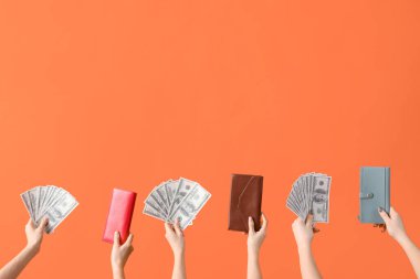 Turuncu arka planda dolar banknotları ve cüzdanları olan kadınlar.
