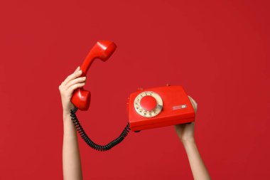 Kırmızı arka planda klasik telefon tutan kadın eller. Sevgililer Günü kutlaması