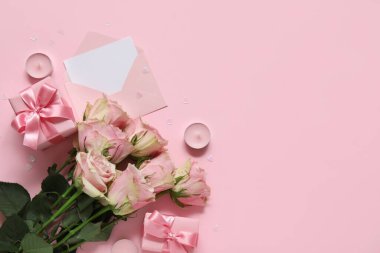 İçinde boş tebrik kartı, hediye kutusu ve pembe arka planda bir buket gül olan bir zarf. Sevgililer Günü kutlaması