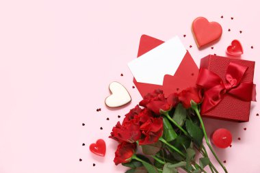 İçinde boş tebrik kartı, kalpler, hediye kutusu ve pembe arka planda bir buket gül olan bir zarf. Sevgililer Günü kutlaması